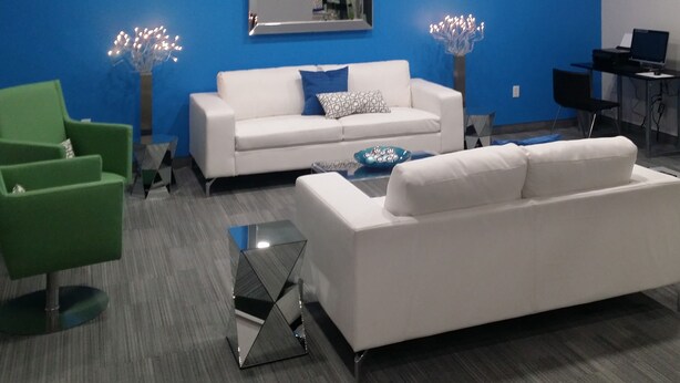 A modern living room with a white sofa, green armchair, and a glass coffee table. - Garland Hotel (New Concord)