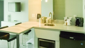A modern kitchen with a built-in microwave, a sink, and a coffee maker. - Garland Hotel (New Concord)