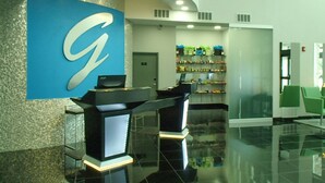 A reception area with a large blue logo, a reception desk, and a shelf with products. - Garland Hotel (New Concord)
