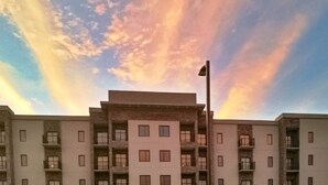 A multi-story building with balconies and a flagpole. - Garland Hotel (New Concord)