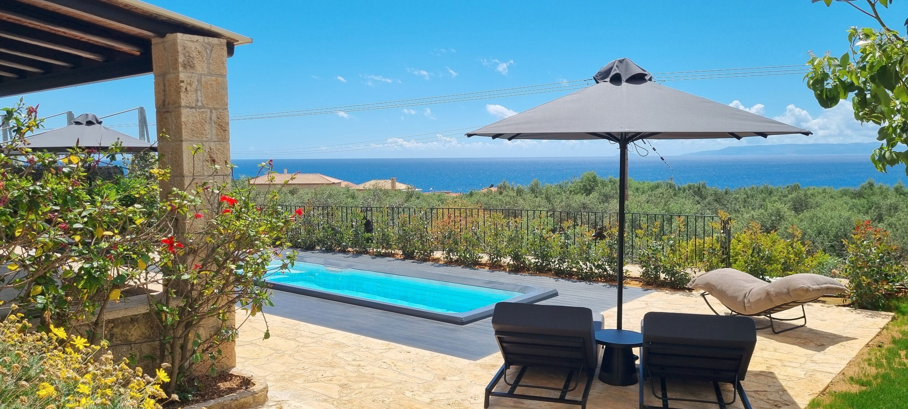 A pool area with a view of the ocean, outdoor seating, and a pergola.