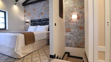 A bedroom with a bed, a stone wall, and a door.