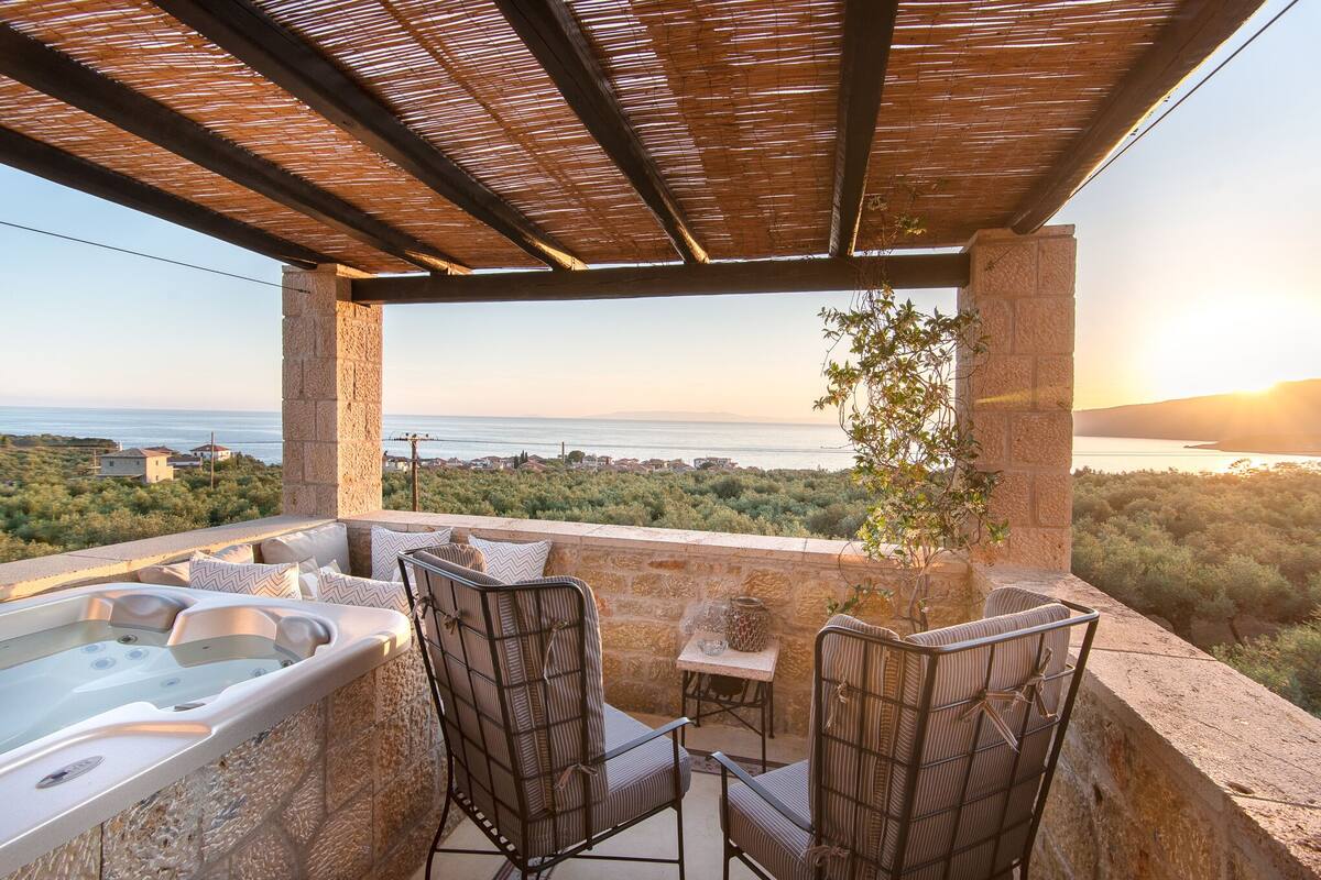 A balcony with a hot tub, wicker chairs, and a view of the sea.