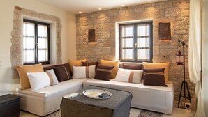 A cozy living room with a stone wall, a striped sofa, and a coffee table with a tray. - Polismata - Private Residences (West Mani)