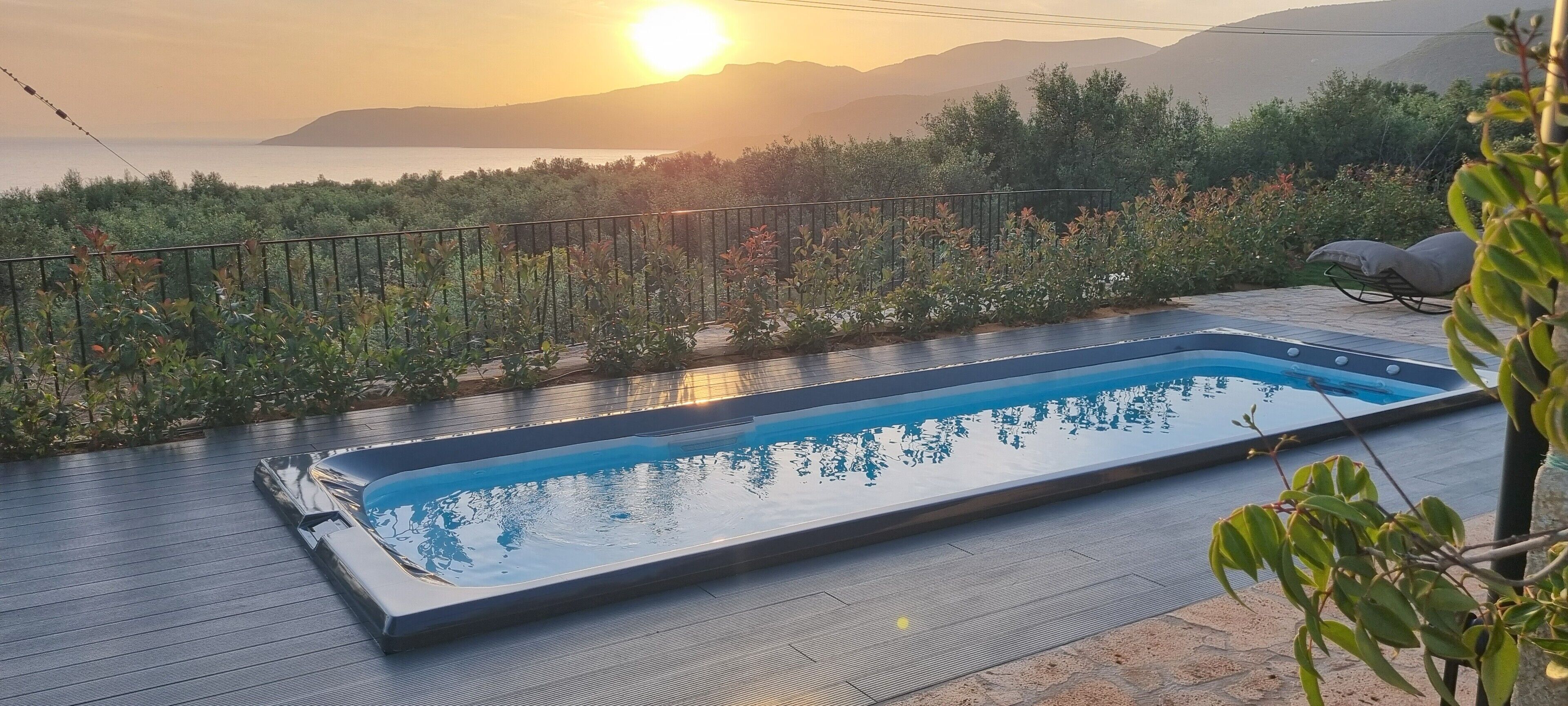A swimming pool with a view of the sea and mountains.