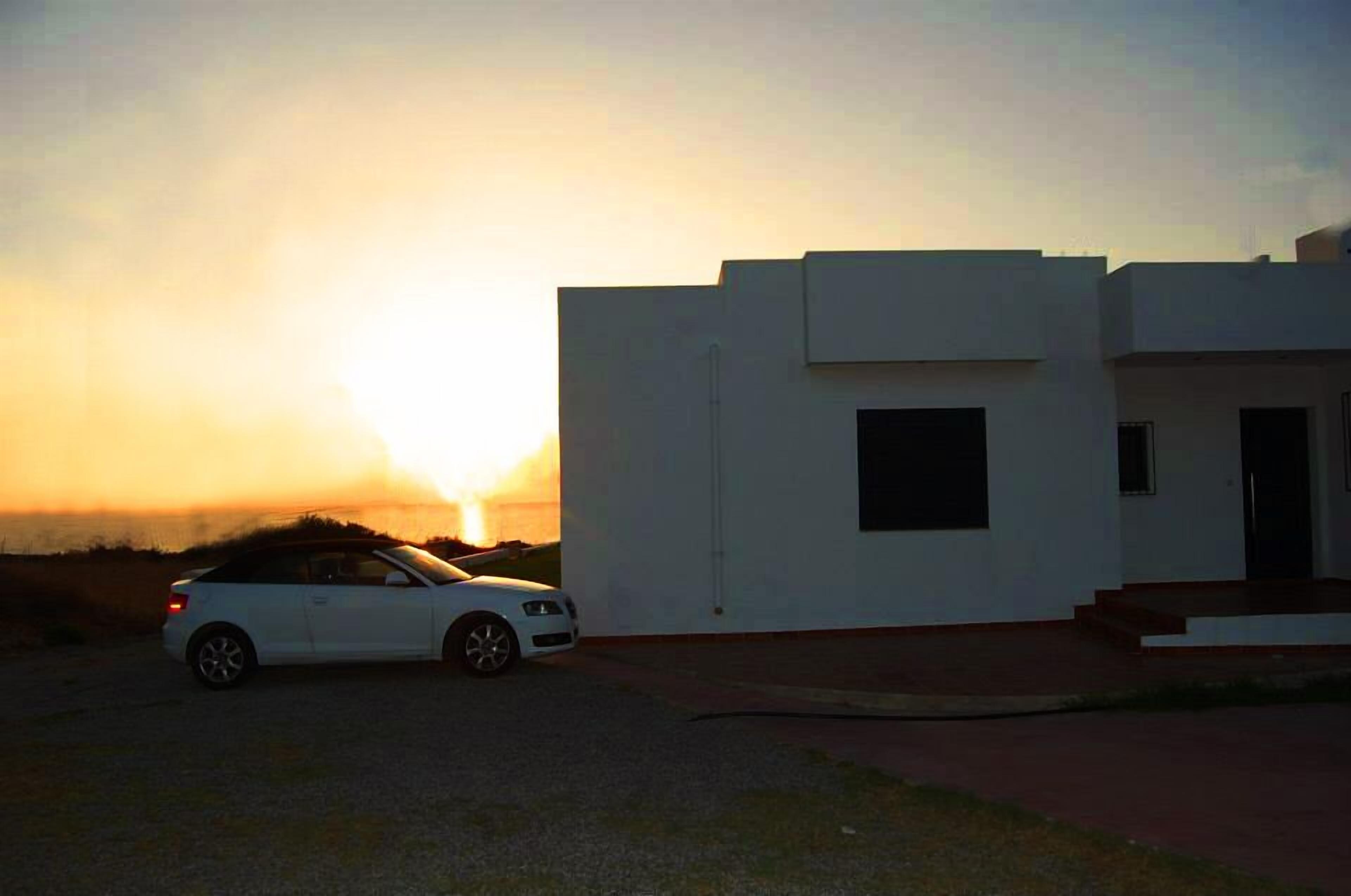 A modern building with a white facade and a car parked in front.