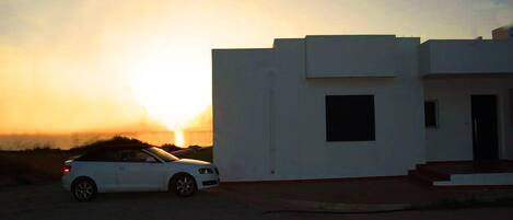 A modern building with a white facade and a car parked in front.