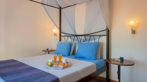 A bed with a canopy, two bedside tables, and a small table with a cup and a plate of food.