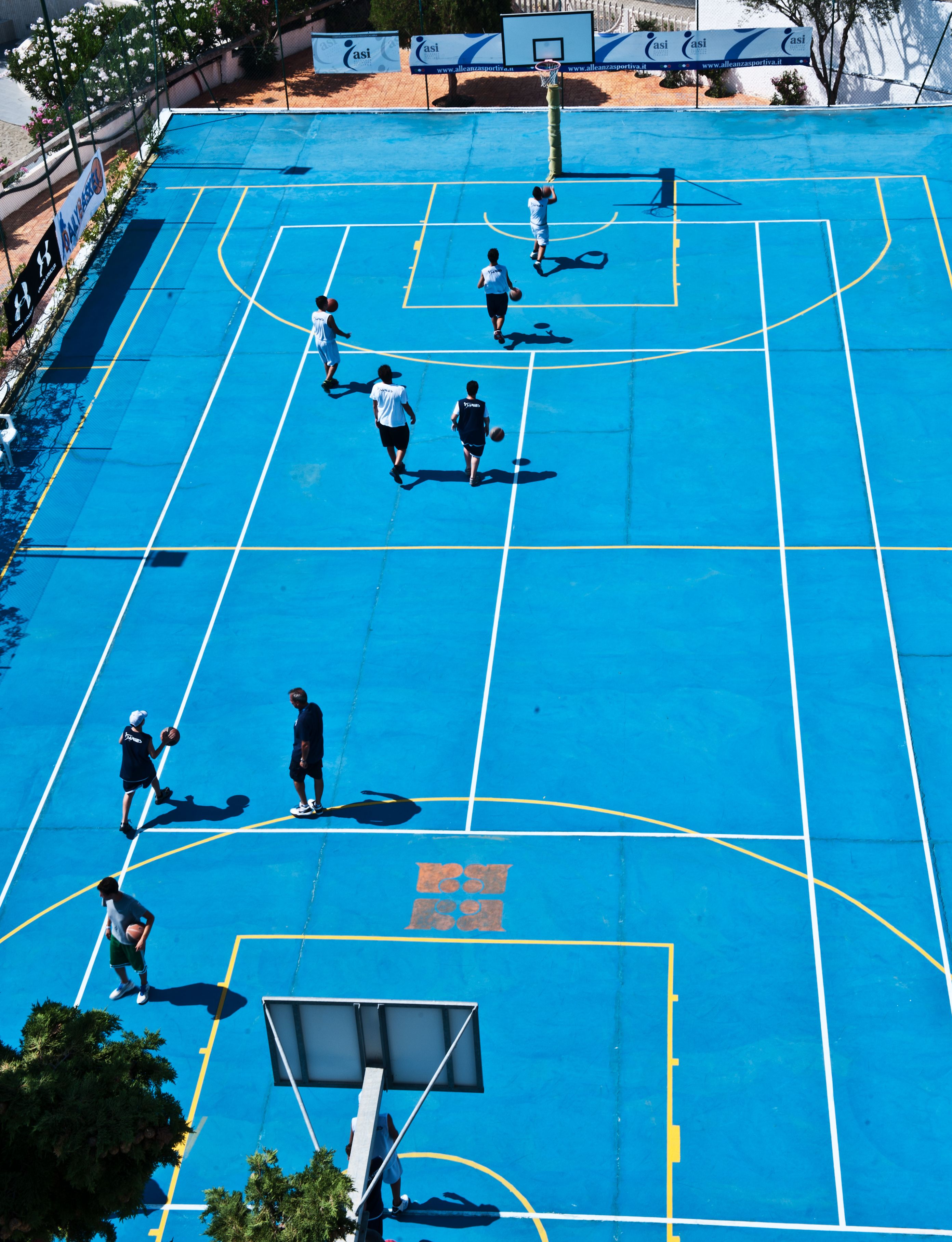 An outdoor basketball court with players and a hoop.