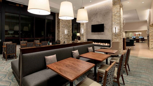 Eine moderne Hotellobby mit Kamin, Sitzbereichen und einem an der Wand montierten Fernseher.