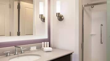 Un baño con un espejo grande, dos luces empotradas, un lavabo con grifo y una zona de ducha.