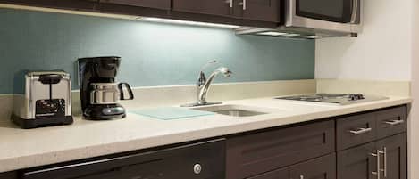 A modern kitchen with dark cabinets, a stainless steel microwave, a coffee maker, and a dishwasher.