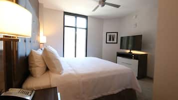 Ein Hotelzimmer mit Bett, Nachttischlampe, Schreibtisch und Fernseher.