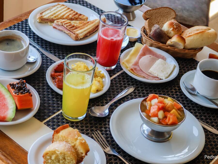 Ein Frühstückstisch mit verschiedenen Speisen, darunter Toast, Eier, Schinken und einer Obstschale.
