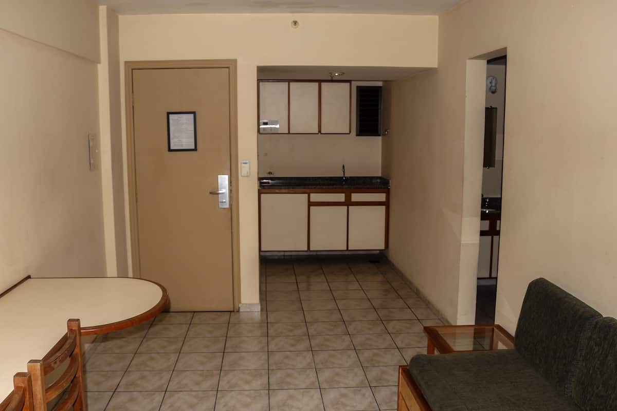 Un espacio habitable compacto con kitchenette, un comedor con mesa y sillas, y un sofá.