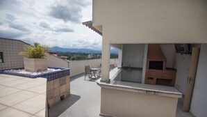 Terraza en la azotea con zona de barbacoa, una planta en maceta y vistas a montañas distantes.