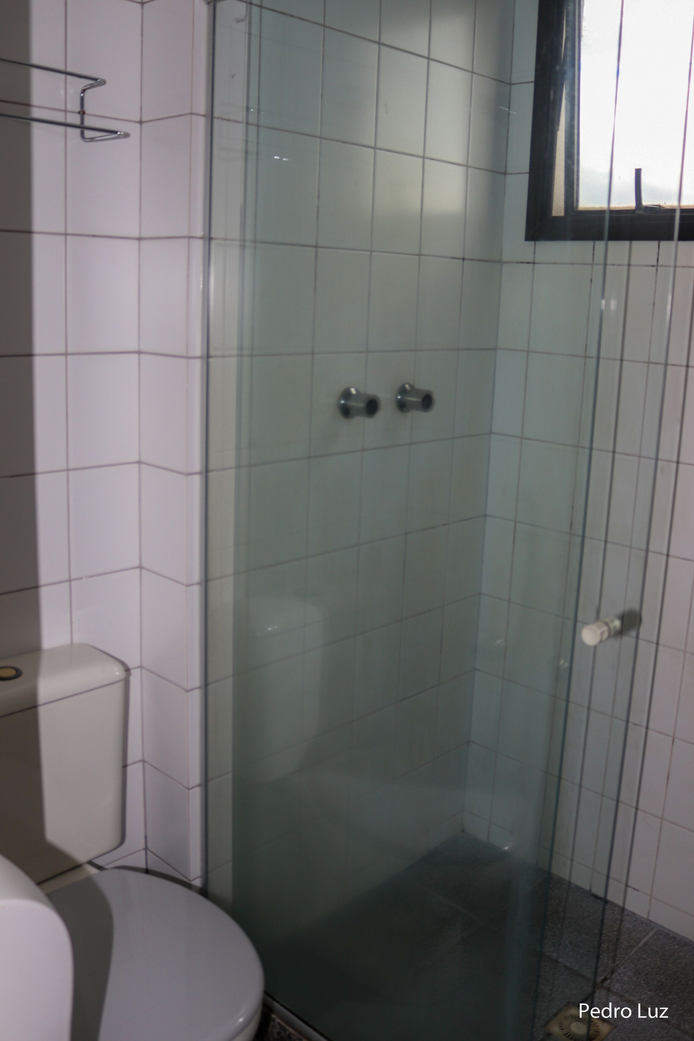Un baño con ducha acristalada, inodoro y paredes de azulejos.