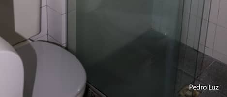 Un baño con ducha acristalada, inodoro y paredes de azulejos.