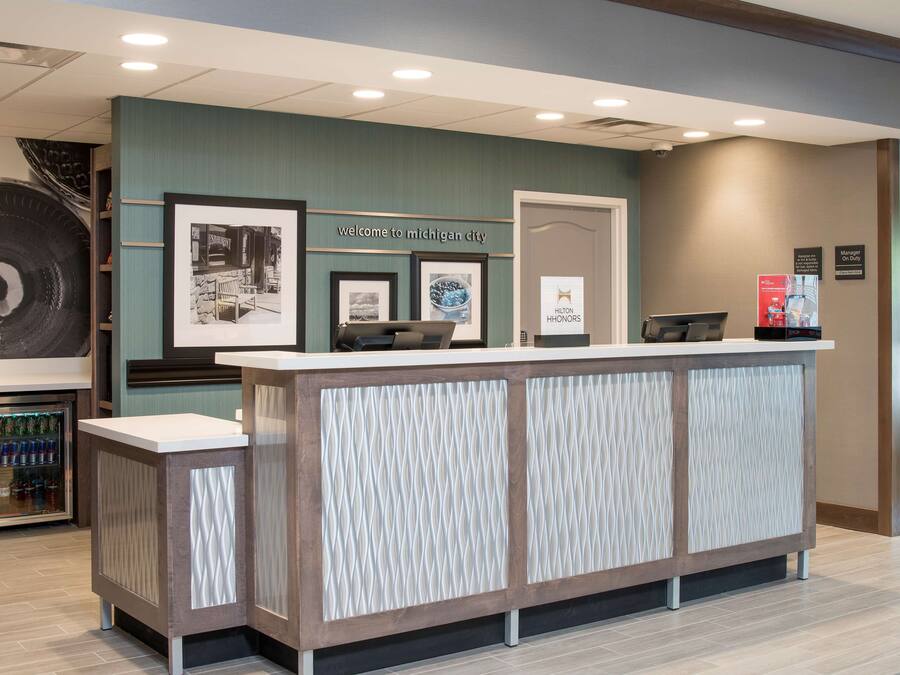 Una reception con un cartello 'Welcome to Michigan City', quadri appesi, un minibar e un cartello 'Responsabile di turno'.