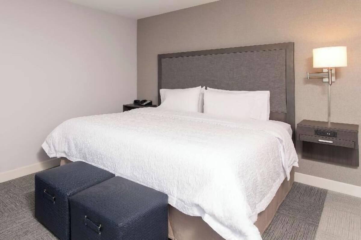 A hotel room with a large bed, a bedside table, a lamp, and a suitcase.