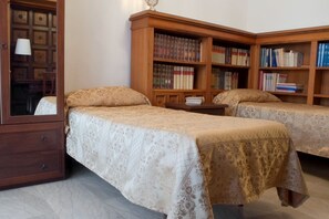 A room with two beds, a wooden cabinet with books, and a lamp. - Attico dei Pini (Rome)