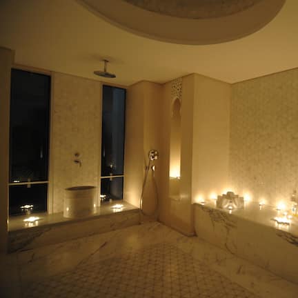 A luxurious bathroom with a marble sink, a bathtub, and candles.