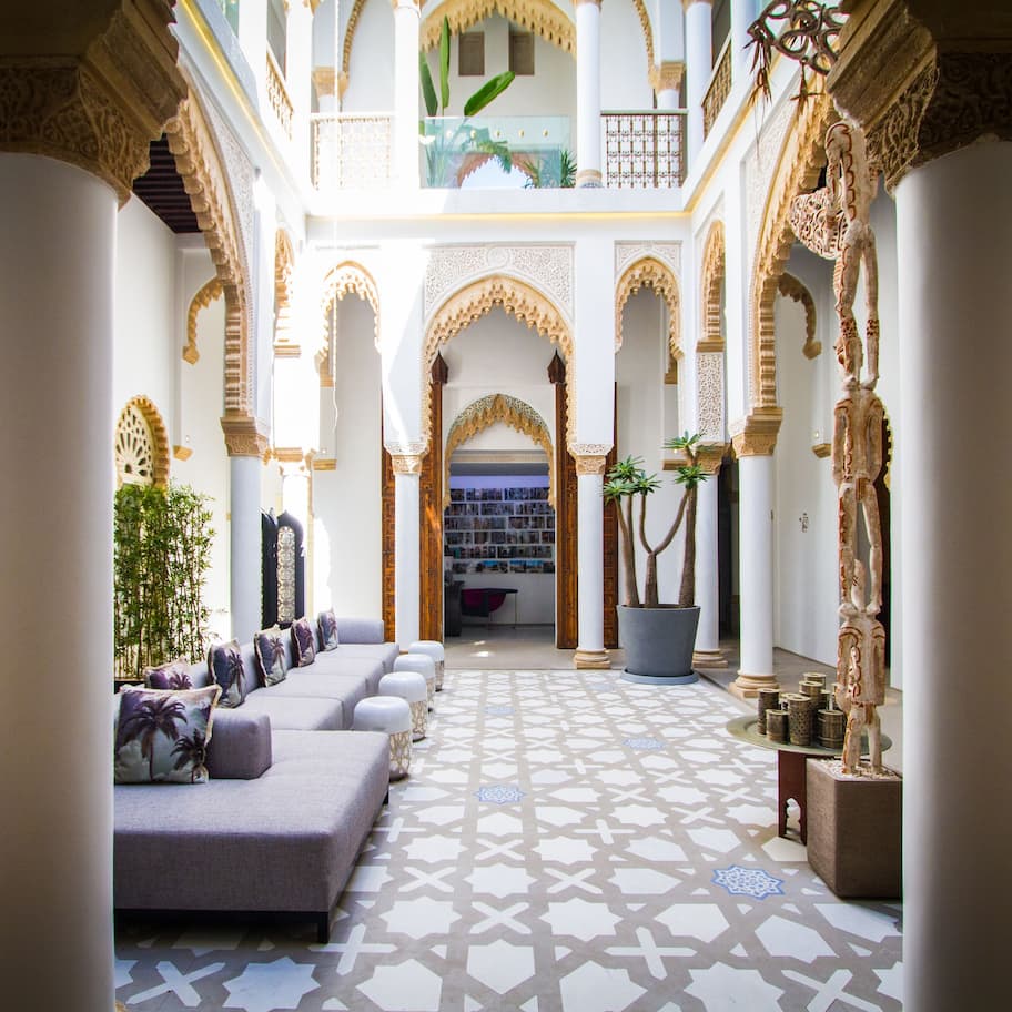 A spacious atrium with high ceilings, ornate arches, and a central seating area with cushions.