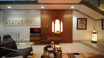 A modern living room with a glass table, a sofa, a decorative cabinet, and a television.