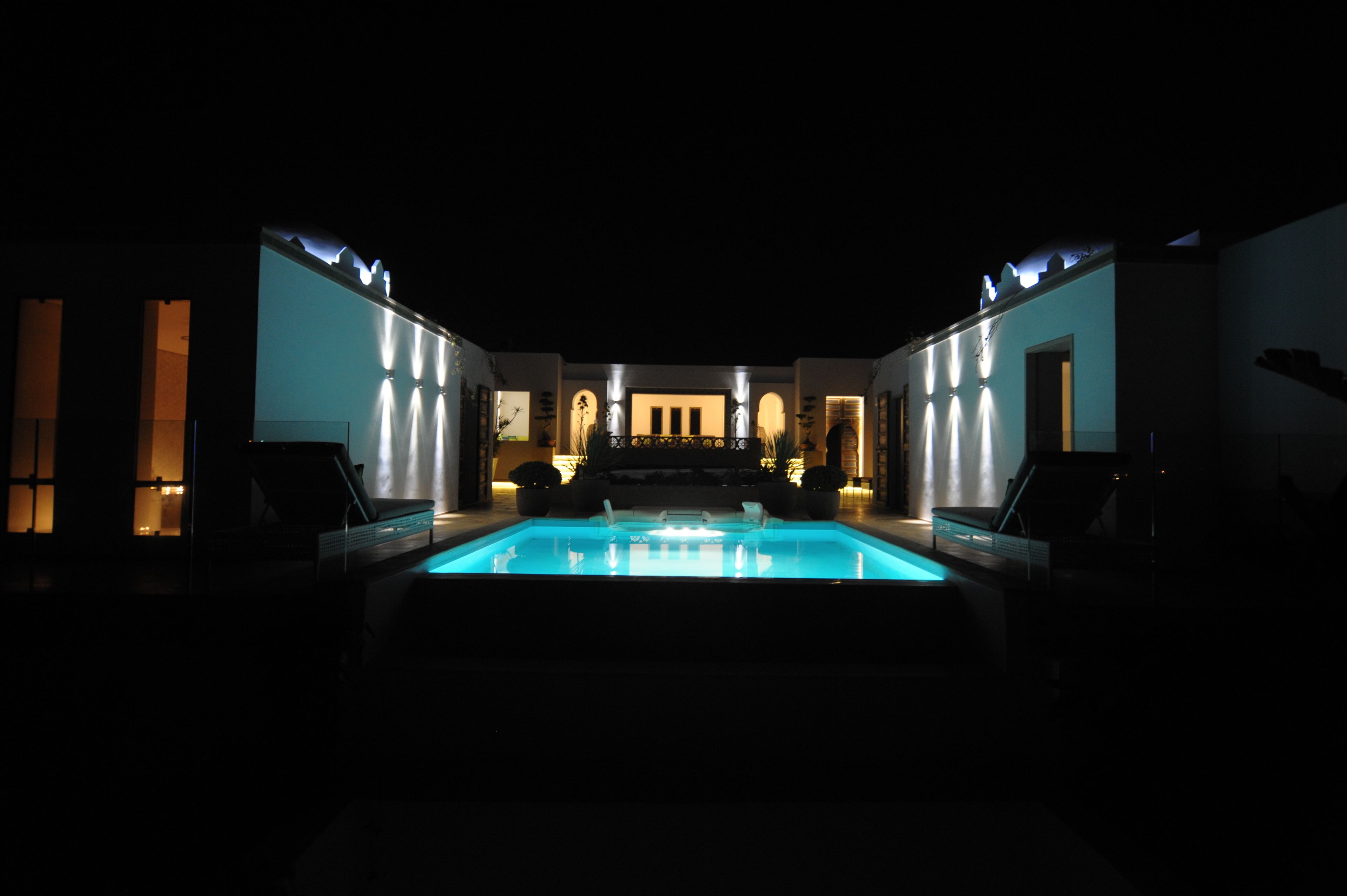 A pool area with a view of a building with multiple arches and a balcony.