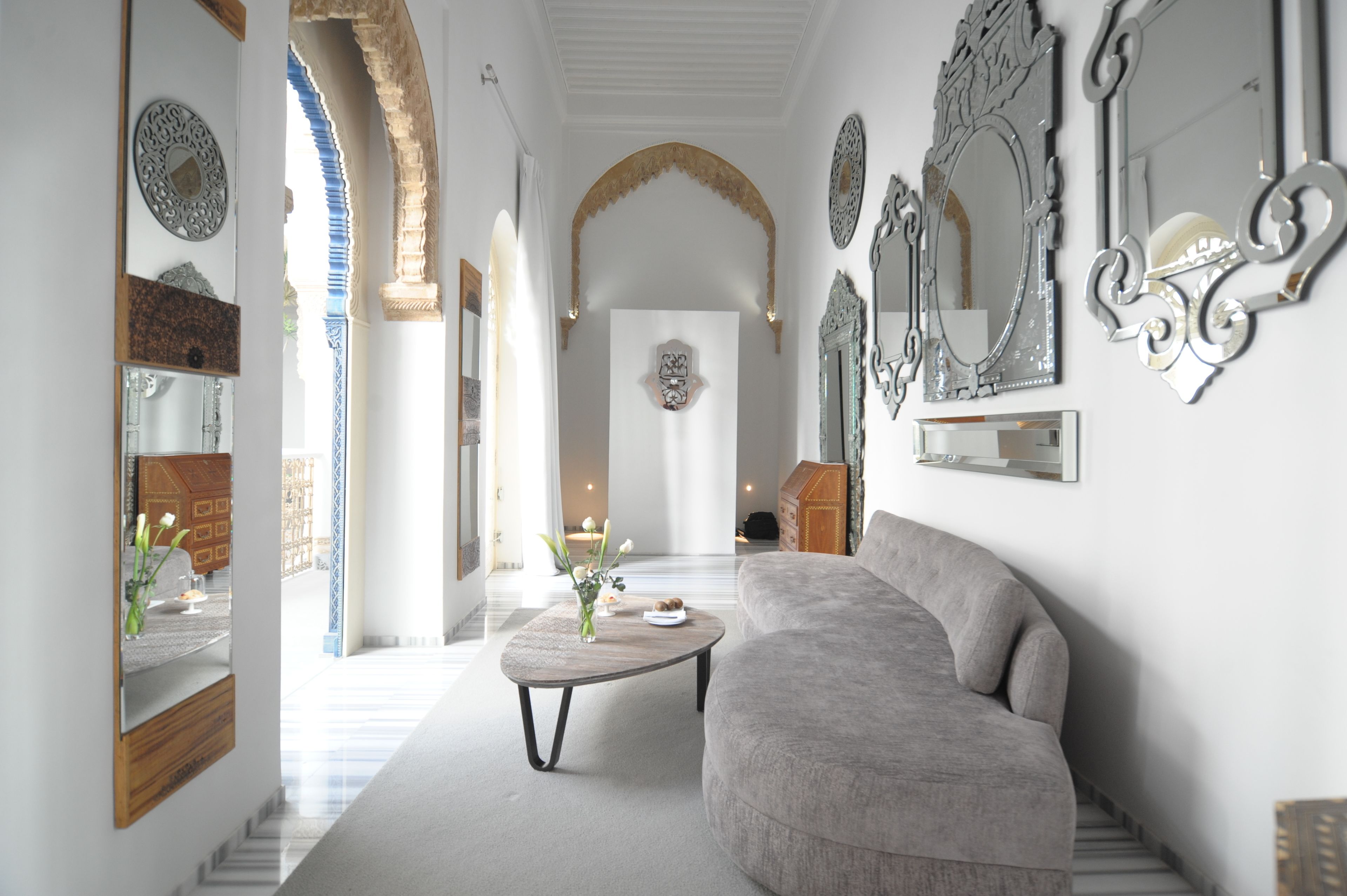 A modern living room with a grey sofa, a coffee table, and decorative mirrors.