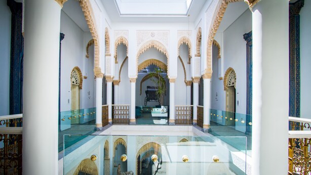 Un intérieur spacieux avec un espace central ouvert, des arches décoratives et un plancher en verre.