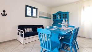 Una habitación con una mesa de comedor azul, sillas a juego, un sofá blanco y un mueble azul.