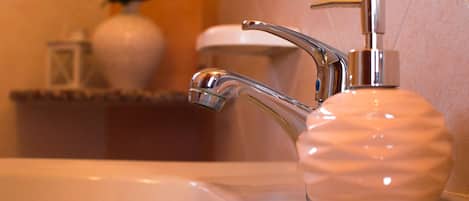 Un lavabo de baño con grifo cromado y dispensador de jabón.