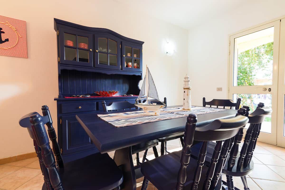 A dining area with a dark blue table, matching chairs, and a cabinet with glass doors.