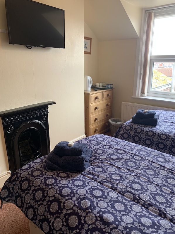 Un dormitorio con dos camas, televisión, cómoda y ventana con vistas.