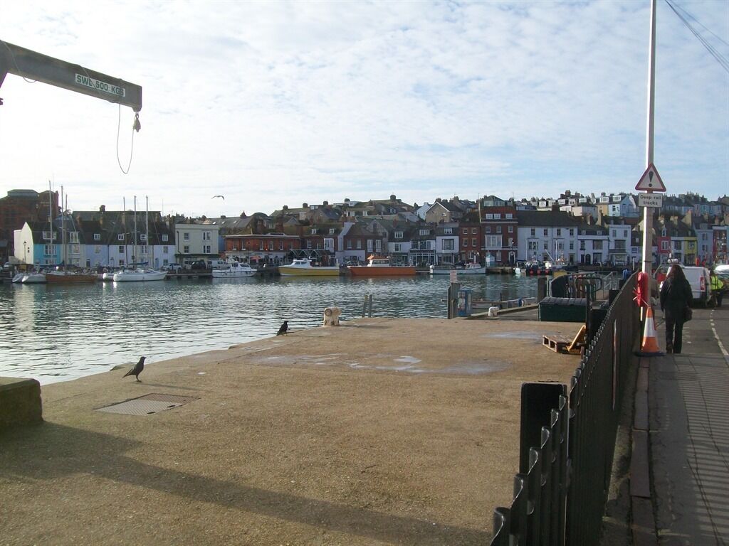 A harbor with boats, a crane, and buildings along the waterfront.