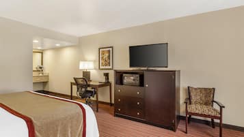 Una habitación de hotel con una cama, un escritorio con silla, un televisor y un armario.