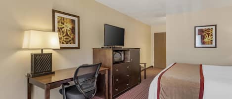 A hotel room with a bed, a desk with a chair, a television, and a microwave.