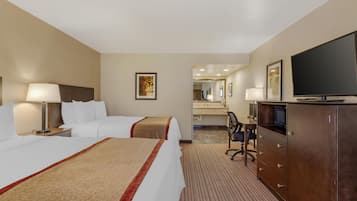 A hotel room with two beds, a desk with a chair, a television, and a mirror.