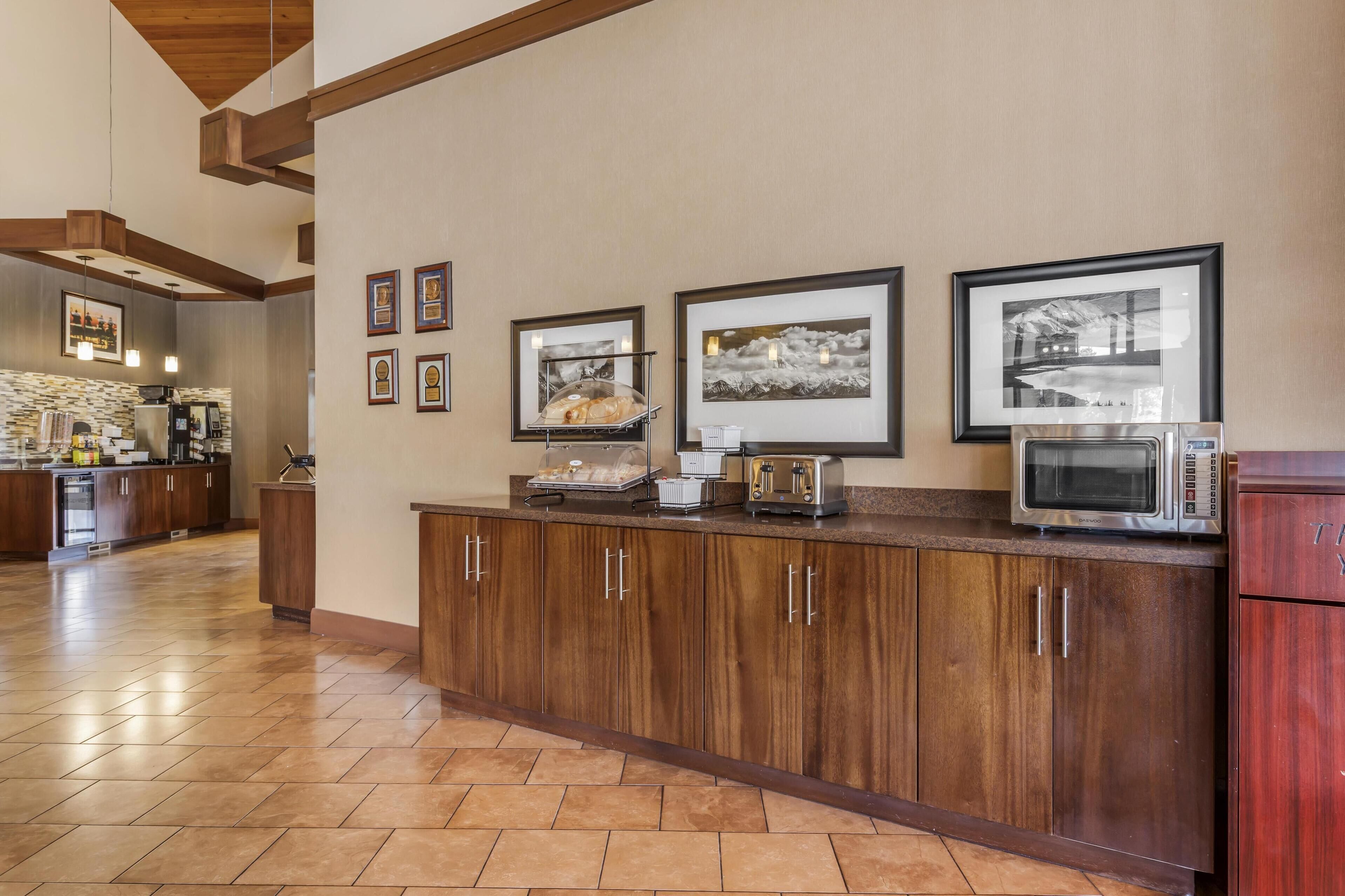 A kitchen with wooden cabinets, a microwave, a toaster, and framed pictures on the wall.