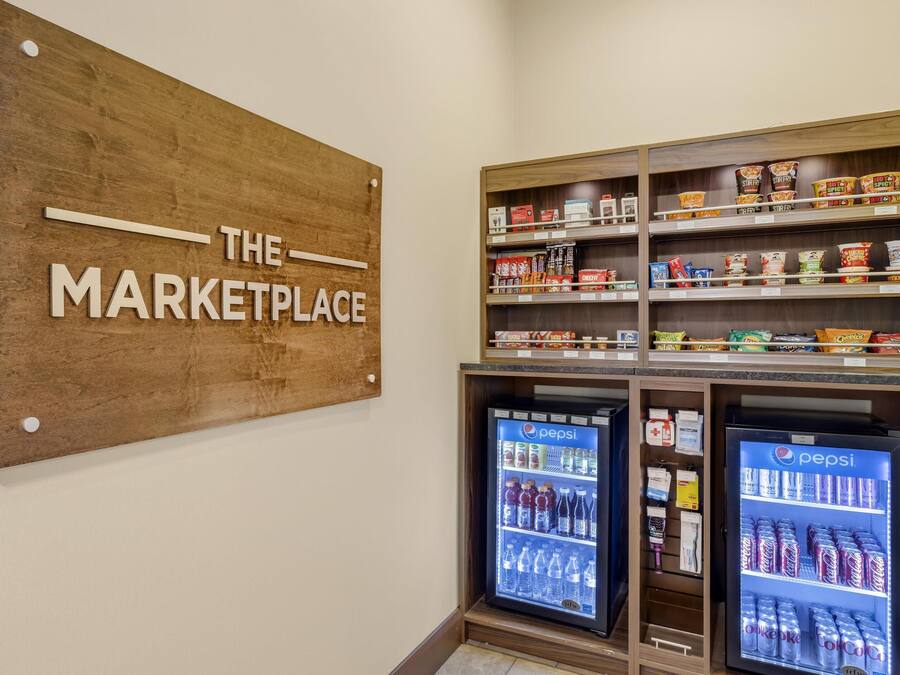 A wooden sign reading "THE MARKETPLACE" above shelves stocked with snacks and beverages, including Pepsi and Coca-Cola.