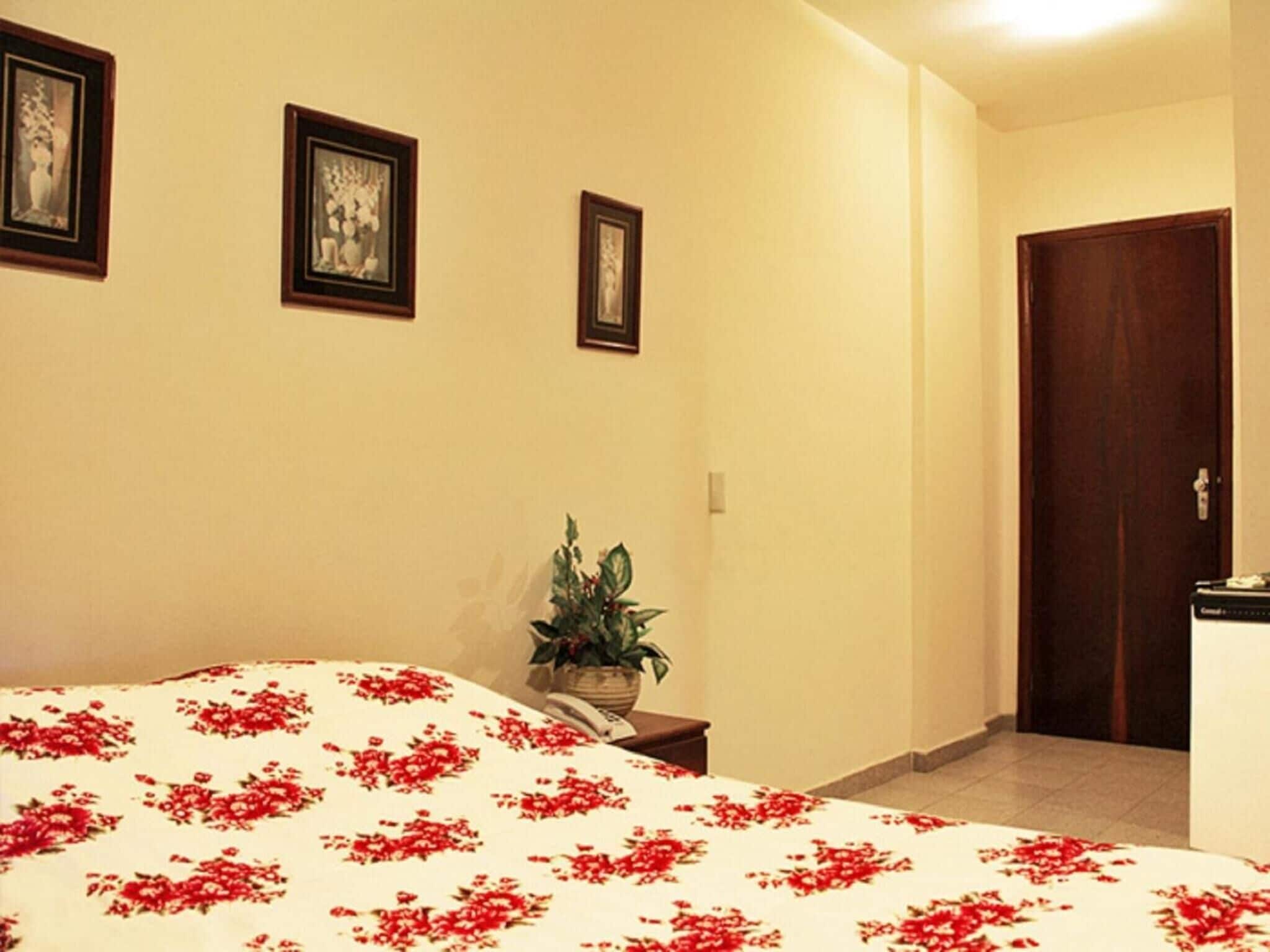 Una habitación de hotel con una cama, una planta en maceta y una puerta.