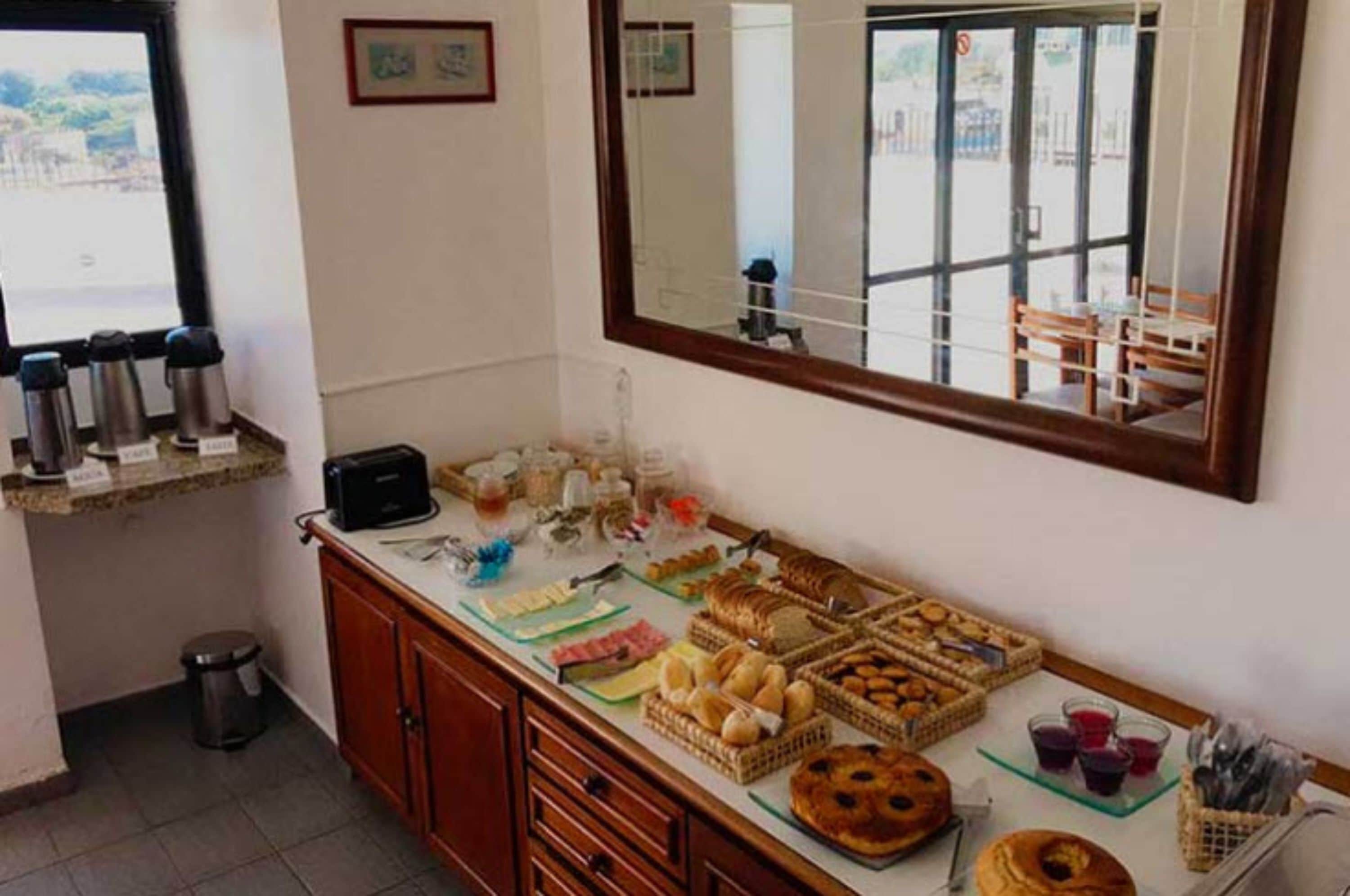 A breakfast buffet with various pastries, breads, and beverages.