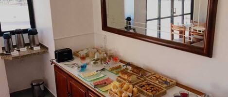 A breakfast buffet with various pastries, breads, and beverages.
