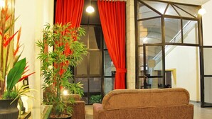A modern living room with a sofa, a dining table with chairs, and potted plants. - Scala Residence Hotel (Resende)