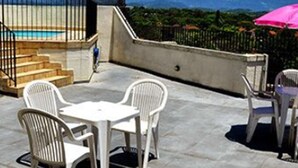 A terrace with a pool, white chairs, and a pink umbrella. - Scala Residence Hotel (Resende)