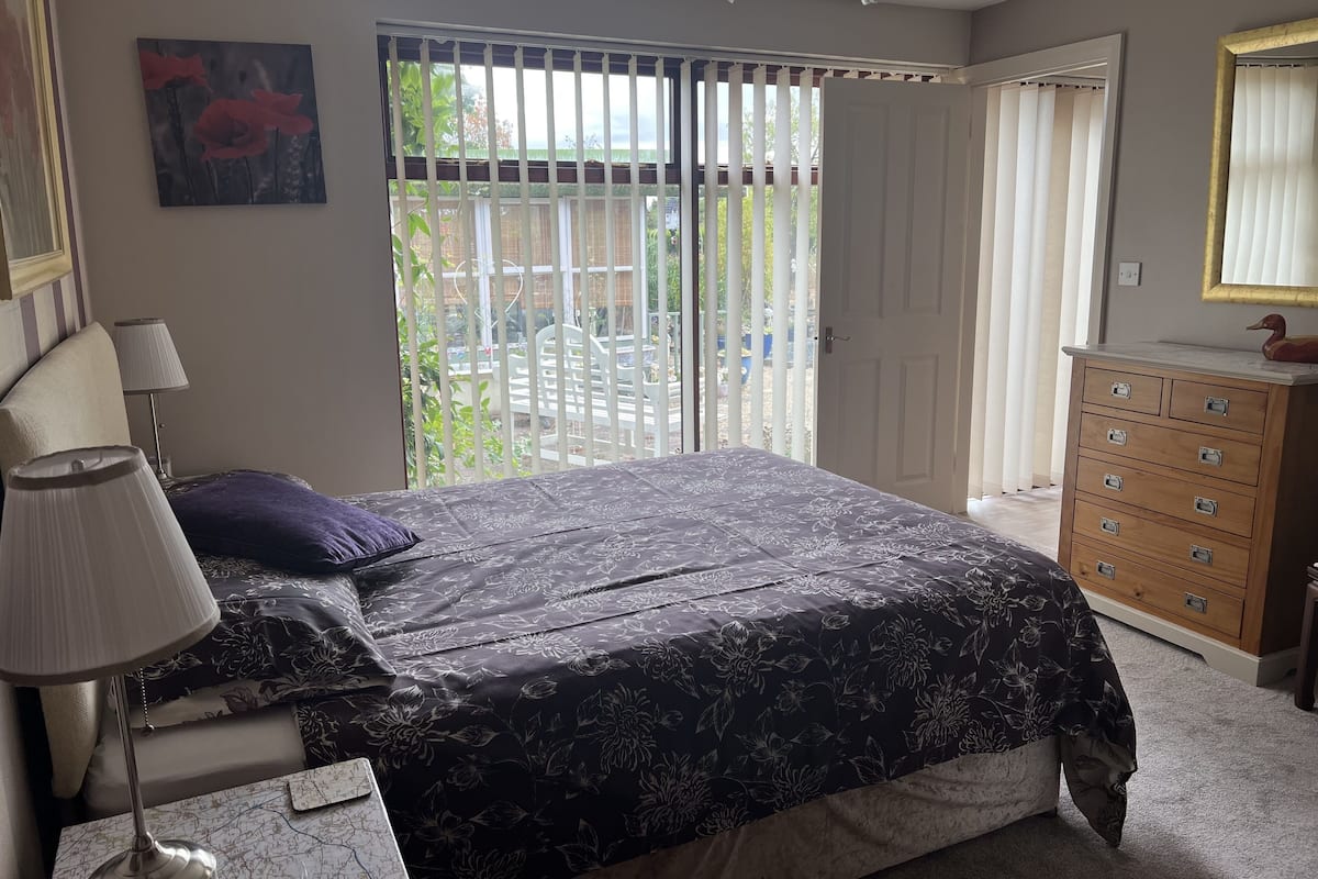 A bedroom with a bed, a dresser, a lamp, and a painting on the wall.