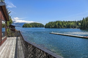 Una terraza de madera con vistas a un lago, con un muelle que se adentra en el agua.
