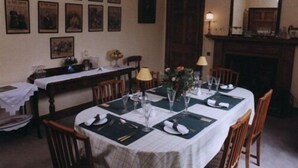 A dining room with a table set for four, framed pictures on the wall, a chandelier, and a fireplace. - Spylaw Bank House (Edinburgh)
