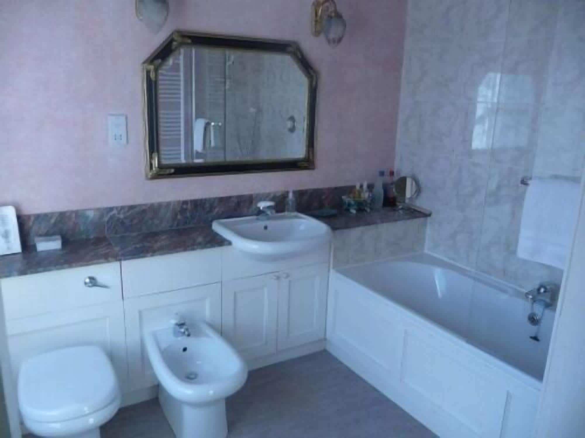 A bathroom with a toilet, bidet, sink, and bathtub.